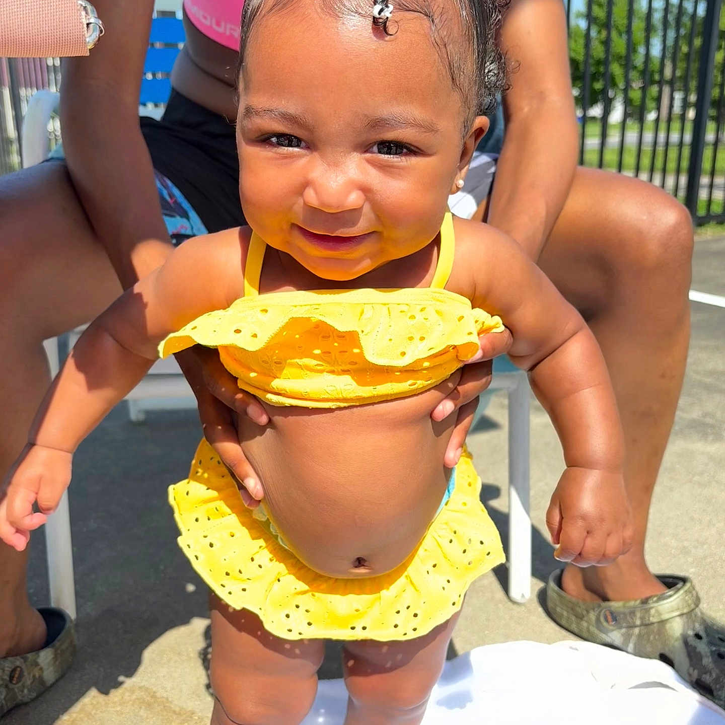 Autumn joined the competition — help win amazing prizes! adult_hands, arms, baby, bow, child, concrete, footwear, hair_bow, happy, holding_hands, legs, outdoor, person, skin, smiling, standing, summer, sunny, toddler, yellow_swimsuit