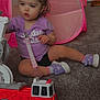 bunny_ears, carpet, child, door, fire_truck, floor, home, indoor, pacifier_clip, pink, play_tent, playtime, purple_shirt, purple_shoes, shorts, sitting, toddler, toy, toy_beads, wet_hair