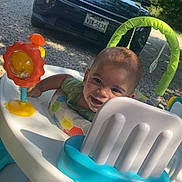 Draven joined the competition — help win amazing prizes! baby, activity_walker, smiling, outdoor, sunlight, car, toy, greenery, gravel, foot, seat, playtime, child, daylight, happy, infant, vehicle, nature, rear_view, colorful