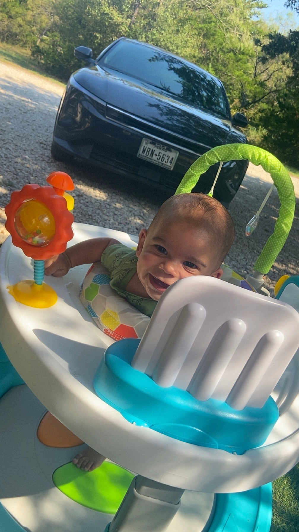Draven joined the competition — help win amazing prizes! baby, activity_walker, smiling, outdoor, sunlight, car, toy, greenery, gravel, foot, seat, playtime, child, daylight, happy, infant, vehicle, nature, rear_view, colorful