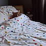 cat, orange_cat, tabby_cat, bed, duvet, polka_dots, pillow, blanket, teddy_bear, toy, curtains, bedroom, bedding, cozy, pet, peeking, fur, pattern, soft, sleepy