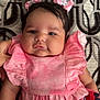 baby, infant, pink_dress, hair_bows, patterned_blanket, chubby_cheeks, cute, child, portrait, lying_down, indoors, soft_fabric, black_hair, hand, smiling, young_child, closeup, adorable, skin, baby_clothing