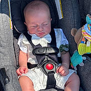 Jaxon joined the competition — help win amazing prizes! baby, sleeping, car_seat, white_outfit, bow_tie, infant, child, toy, pacifier, strap, seatbelt, gray, clothing, cute, peaceful, indoor, young, person, soft_light, comfort