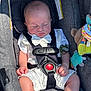 baby, sleeping, car_seat, white_outfit, bow_tie, infant, child, toy, pacifier, strap, seatbelt, gray, clothing, cute, peaceful, indoor, young, person, soft_light, comfort