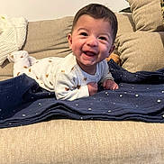 Sohan participe au concours pour gagner de l'argent avec cette photo : baby, smiling, infant, onesie, blanket, couch, indoor, happy, face, child, cute, lying_down, cozy, home, furniture, patterned_clothing, star_pattern, toddler, joyful, portrait