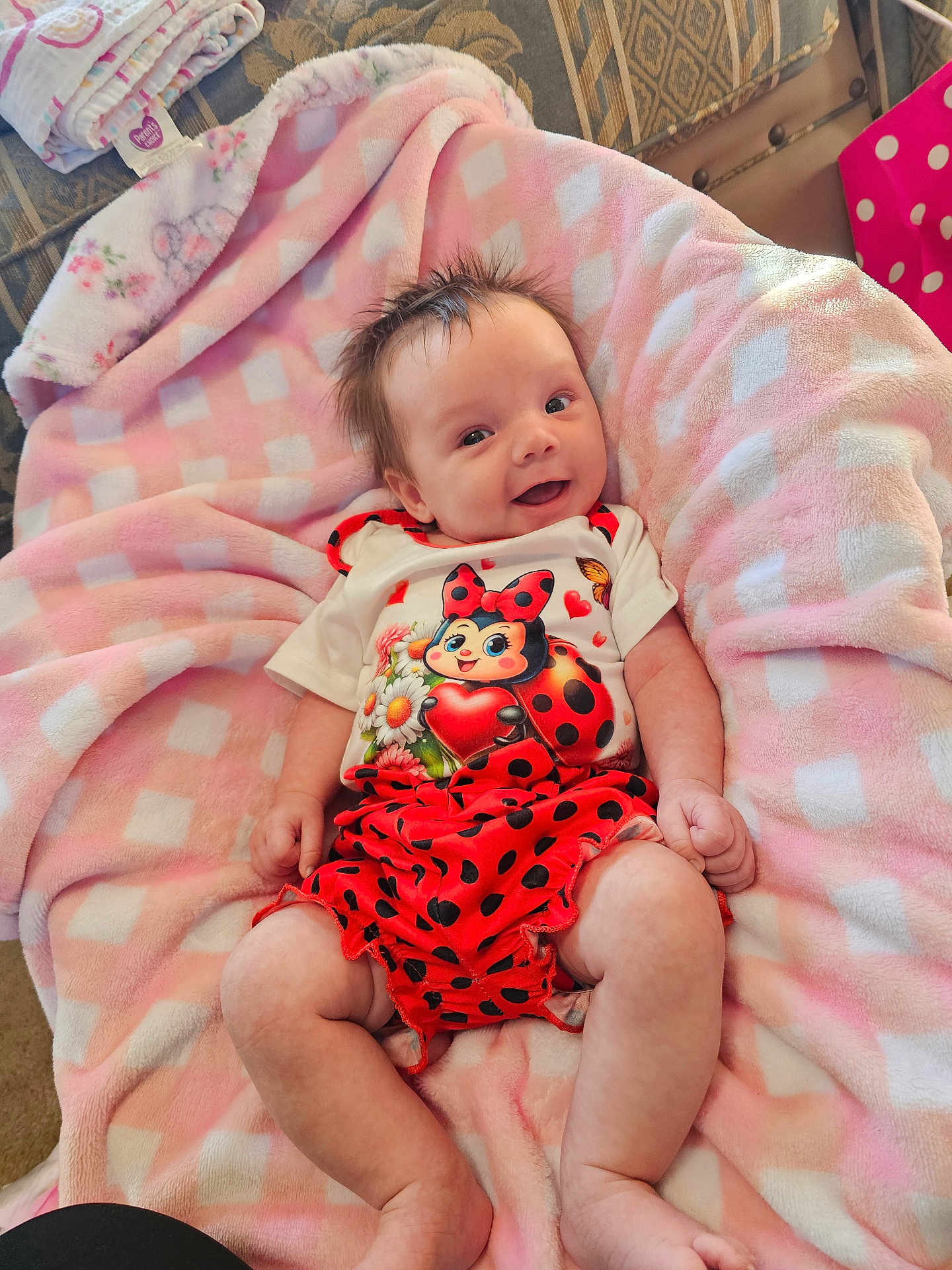Caroline joined the competition — help win amazing prizes! baby, infant, smiling, blanket, pink, white, clothing, ladybug, pattern, cute, soft, happy, indoor, person, child, legs, face, hair, toddler, cozy
