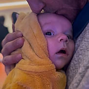 Isaac a rejoint le concours — aidez-le/la à gagner de superbes lots ! baby, adult, hug, kiss, affection, yellow_hood, closeup, face, parent, child, love, warmth, indoor, portrait, cuddle, expression, clothing, skin, hand, emotion