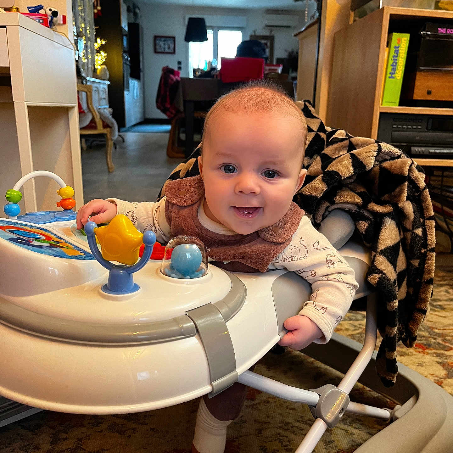 Isaac a rejoint le concours — aidez-le/la à gagner de superbes lots ! baby, blanket, carpet, child, clothing, cozy, cute, face, floor, furniture, happy, home_decor, indoor, living_room, person, play, smile, toy, walker, young_child