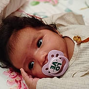 Camila is registered to the contest to win money with this photo: baby, infant, newborn, child, portrait, face, eyes, pacifier, blanket, bed, bedding, floral, indoors, sleeping, lying_down, clothing, cozy, cute, close_up, nursery