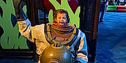 Ezra is registered to the contest to win money with this photo: aquarium, blue_floor, child, curious, display, diving_suit, exhibit, family, fun, helmet, indoor, metal, museum, people, play_area, ripley, sign, smiling, vintage, waving