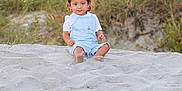 Ezra joined the competition — help win amazing prizes! toddler, child, sand, beach, overalls, grass, outdoor, nature, smile, portrait, young_child, summer, barefoot, daylight, casual_clothing, sitting, curious, person, head, face