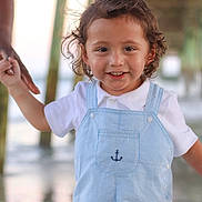 Ezra joined the competition — help win amazing prizes! toddler, child, smiling, curly_hair, holding_hand, overalls, white_shirt, outdoor, pier, water, beach, sunlight, happy, portrait, person, cute, young_child, summer, daylight, family