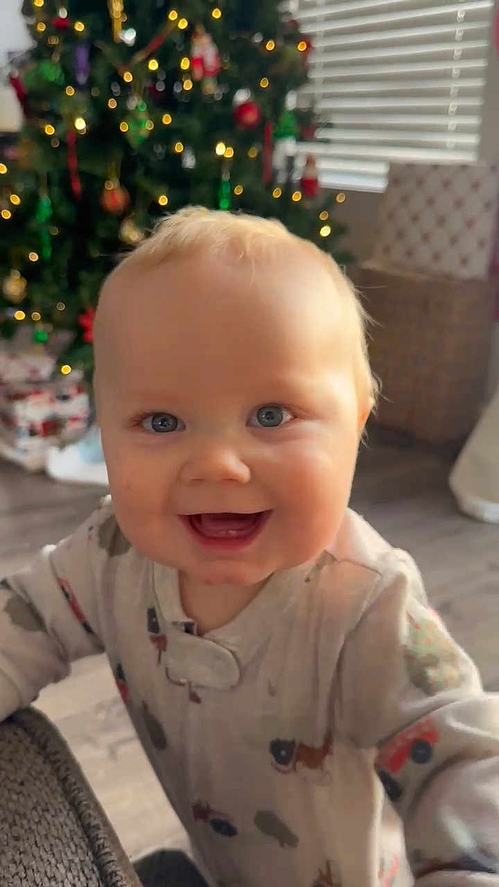 Wade joined the competition — help win amazing prizes! baby, infant, child, smiling, blue_eyes, blond_hair, christmas_tree, ornaments, bokeh, pajamas, teeth, indoor, hardwood_floor, blinds, gift_wrapping, wicker_basket, holiday, cute, portrait, closeup