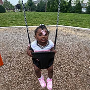 Jersey Gibson is registered to the contest to win money with this photo: toddler, child, swing, playground, grass, trees, house, park, outdoor, sneakers, pink, hair_clip, smiling, person, daylight, wood_chips, play, fun, casual_clothing, happy