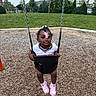 toddler, child, swing, playground, grass, trees, house, park, outdoor, sneakers, pink, hair_clip, smiling, person, daylight, wood_chips, play, fun, casual_clothing, happy