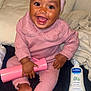 baby, blanket, bottle, child, clothing, cute, face, feet, hand, happy, headband, indoors, infant, lotion, person, pillow, pink_outfit, sitting, skin_care, smiling
