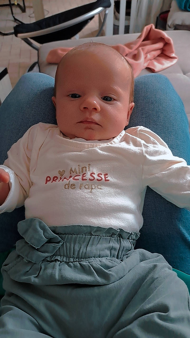 Mya participe au concours pour gagner de l'argent avec cette photo : baby, baby_products, baby_toddler_clothing, chair, cheek, child, chin, comfort, eye, facial_expression, hairstyle, lap, linens, mouth, person, pink, sitting, skin, sleeve, t_shirt