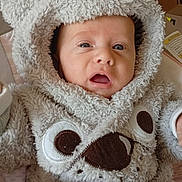 Gabriel participe au concours pour gagner de l'argent avec cette photo : baby, child, fuzzy_clothing, hooded_outfit, bear_design, cute, infant, face, expression, blue_eyes, soft_texture, warm, indoors, seat, apparel, young_child, portrait, closeup, adorable, cozy