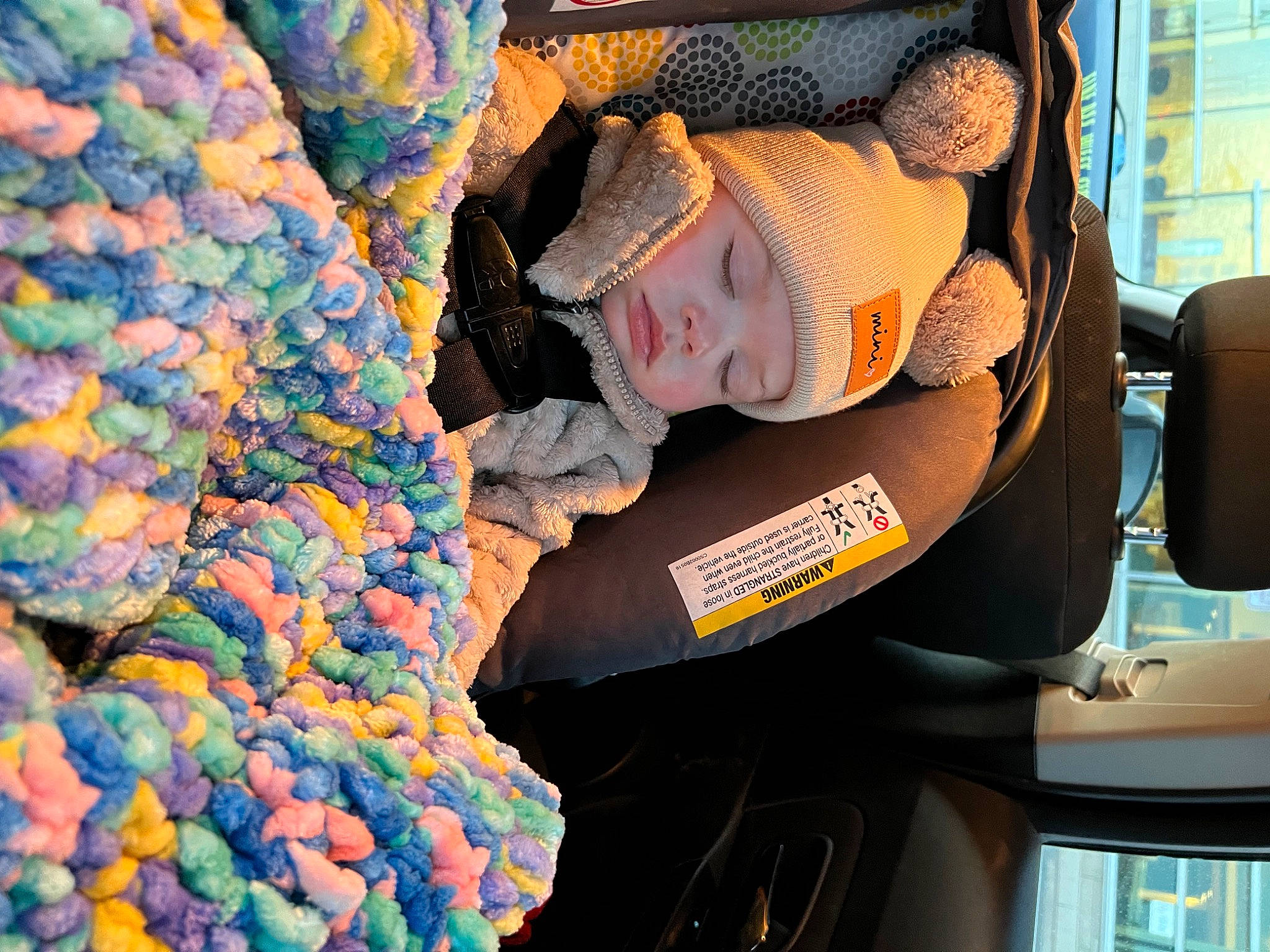 Everly is registered to the contest to win money with this photo: baby, baby_products, beanie, cap, car_seat, car_seat_cover, family_car, fun, hat, headwear, helmet, knit_cap, motor_vehicle, pattern, person, plush, steering_wheel, stuffed_toy, toddler, toy