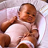 baby, infant, child, pink_clothing, baby_seat, footwear, indoors, portrait, face, relaxed, cute, soft_lighting, skin, hand, expression, cozy, cushion, seat, earrings, newborn
