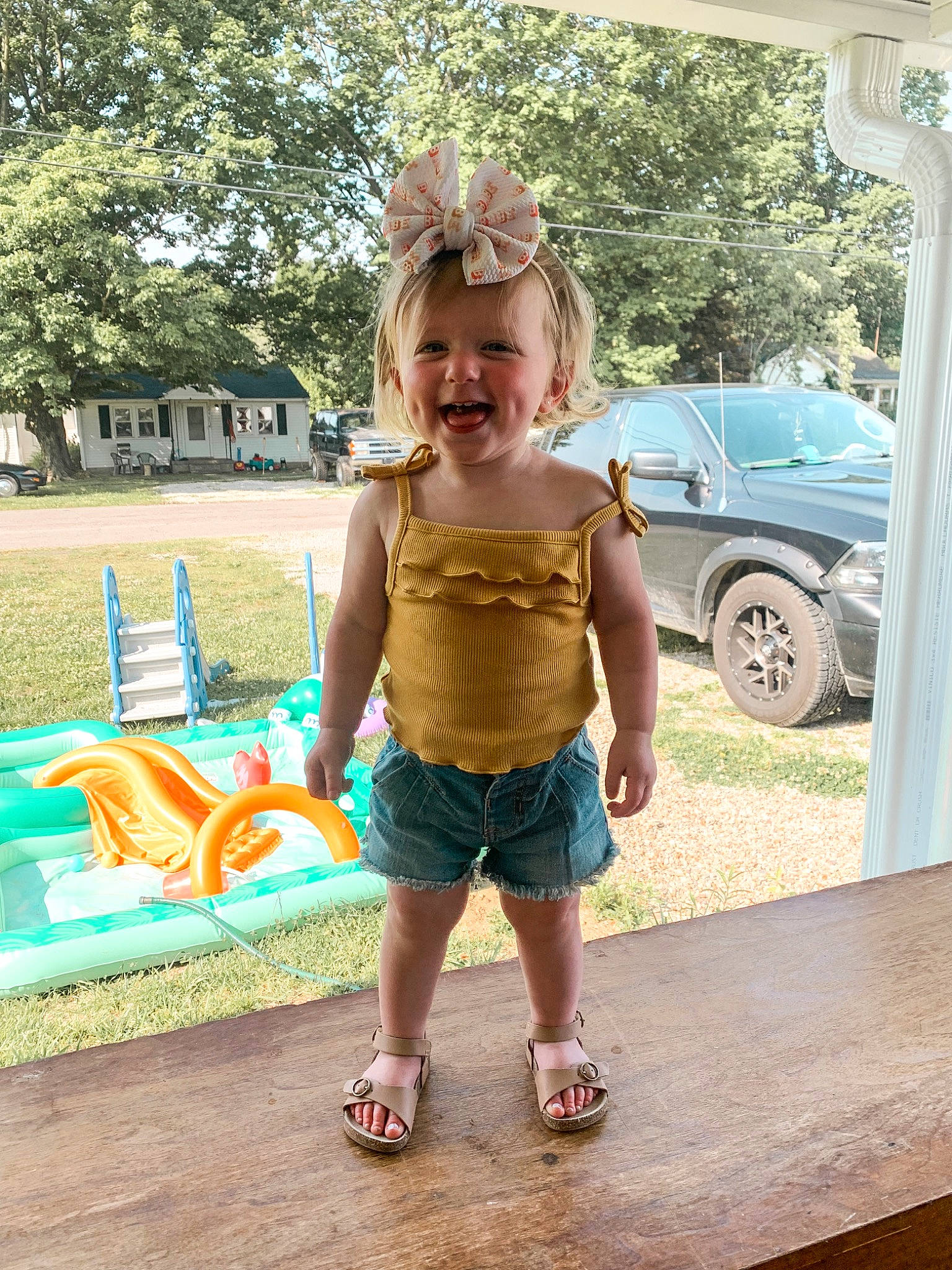 Roxanne is registered to the contest to win money with this photo: car, child, fun, grass, happy, human_leg, leg, leisure, person, plant, recreation, smile, thigh, tire, toddler, tree, trunk, vehicle_door, waist, wheel