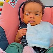 Iris joined the competition — help win amazing prizes! baby, infant, car_seat, pink, bib, clothing, curly_hair, child, seatbelt, hand, footwear, knit_socks, outdoor, portrait, person, cute, small, young, toddler, resting
