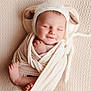 baby, newborn, infant, sleeping, smile, swaddled, knit_hat, ear_detail, toes, feet, blanket, textured_background, cozy, soft_light, portrait, close_up, peaceful, cute, studio, warm_tones