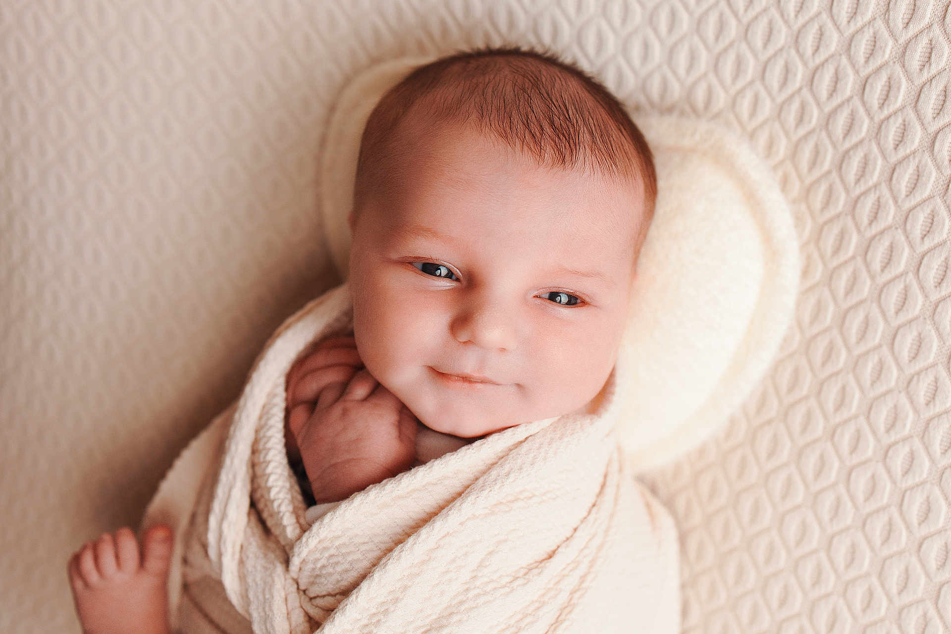 Liam participe au concours pour gagner de l'argent avec cette photo : baby, newborn, infant, swaddle, blanket, portrait, face, eyes, smile, cheeks, head, hair, hand, foot, toes, cozy, soft_lighting, textured_background, close_up, peaceful