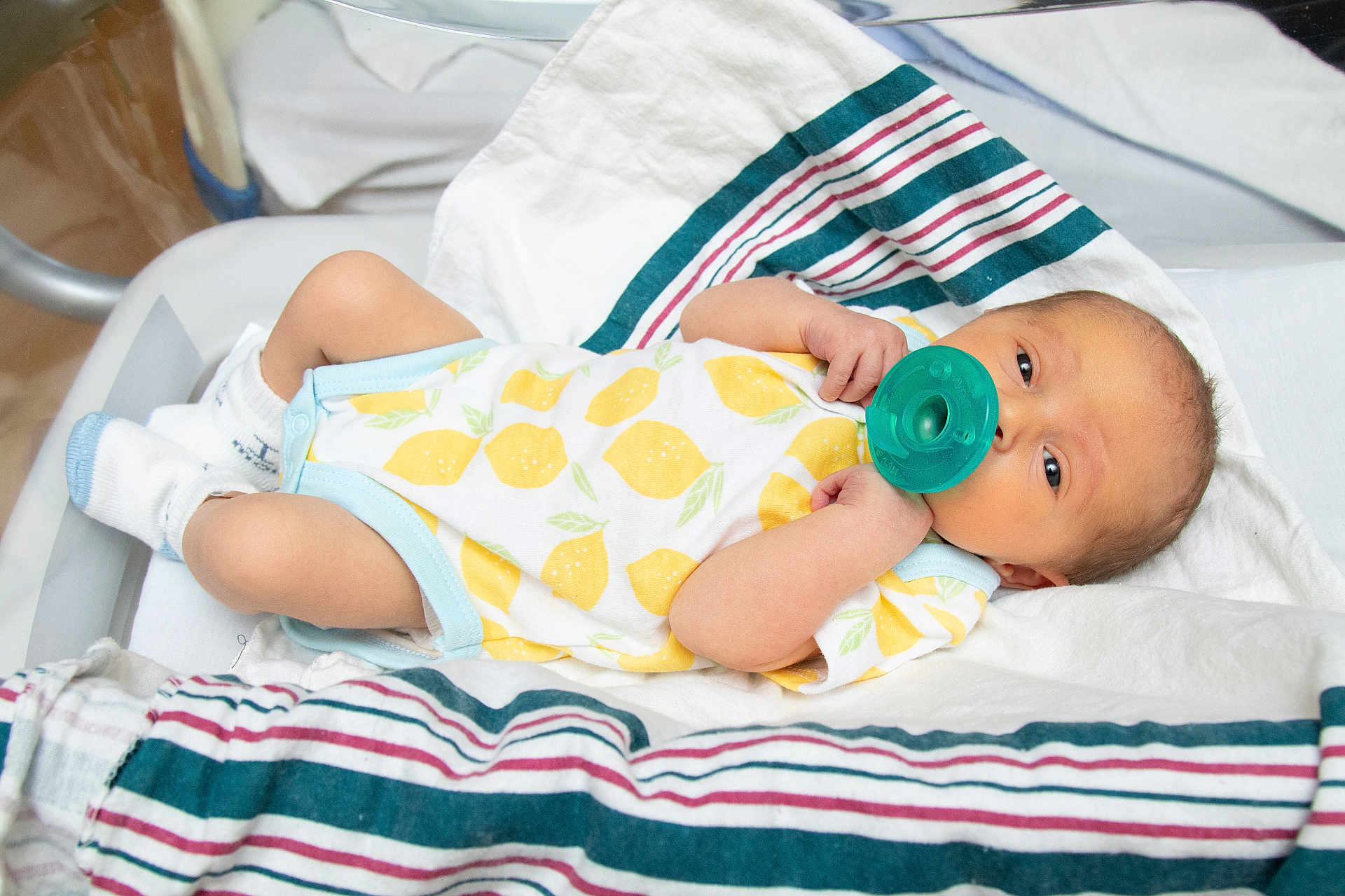 Thomas Ricci Jr is registered to the contest to win money with this photo: newborn, baby, pacifier, hospital_bassinet, onesie, lemon_pattern, socks, blanket, striped_blanket, infant, lying_down, baby_clothing, hospital, sleepy, cute, small_arms, small_legs, skin, face, resting