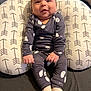 baby, smiling, pajamas, socks, pillow, patterned_pillow, arrows_pattern, ghost_prints, infant, indoor, cute, happy, child, seated, cozy, soft_fabric, hands, face, young_child, portrait