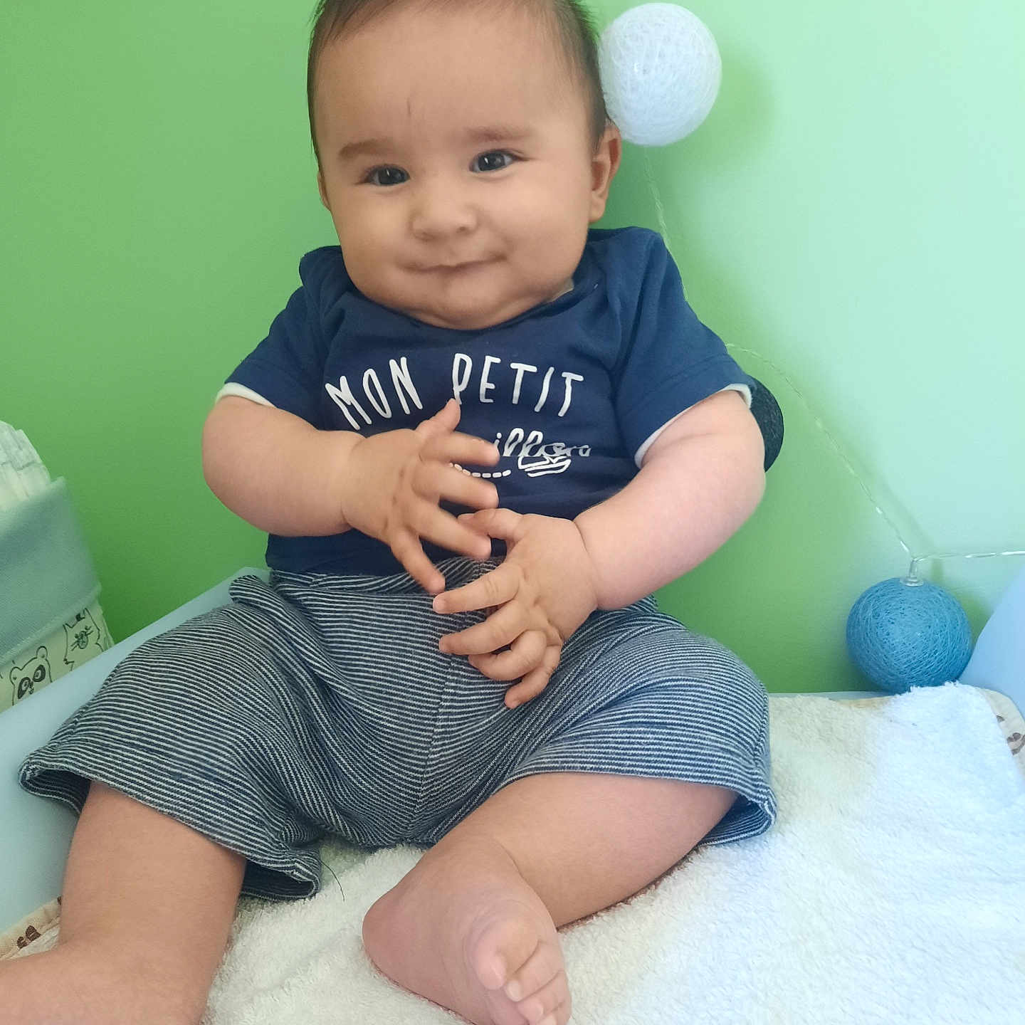 Pablo participe au concours pour gagner de l'argent avec cette photo : baby, child, clothing, cute, face, foot, green_wall, hand, happy, indoors, infant, playful, portrait, shirt, shorts, sitting, skin, smile, soft_surface, young