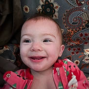 Ellie joined the competition — help win amazing prizes! baby, smile, infant, child, face, onesie, clothing, happy, patterned_background, close_up, young_child, portrait, cute, indoors, baby_girl, cheerful, colorful, fabric, head, skin