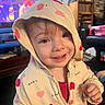baby, candid, casual_clothing, child, closeup, cozy, cute, expression, furniture, happy, heart_pattern, hoodie, indoors, living_room, person, portrait, smiling, television, toddler, warm_lighting
