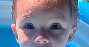 Ellie is registered to the contest to win money with this photo: blue_pool, child, closeup, curious, daytime, face, grass, inflatable_pool, outdoor, playing, portrait, short_hair, summer, sunlight, toddler, water, water_droplets, wet, white_shirt, young_child