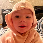 Ellie is registered to the contest to win money with this photo: child, hood, indoor, cozy, blurred, portrait, baby, face, clothing, young, soft_light, warm_tone, blanket, furniture, bedroom, person, expression, cute, casual, close_up