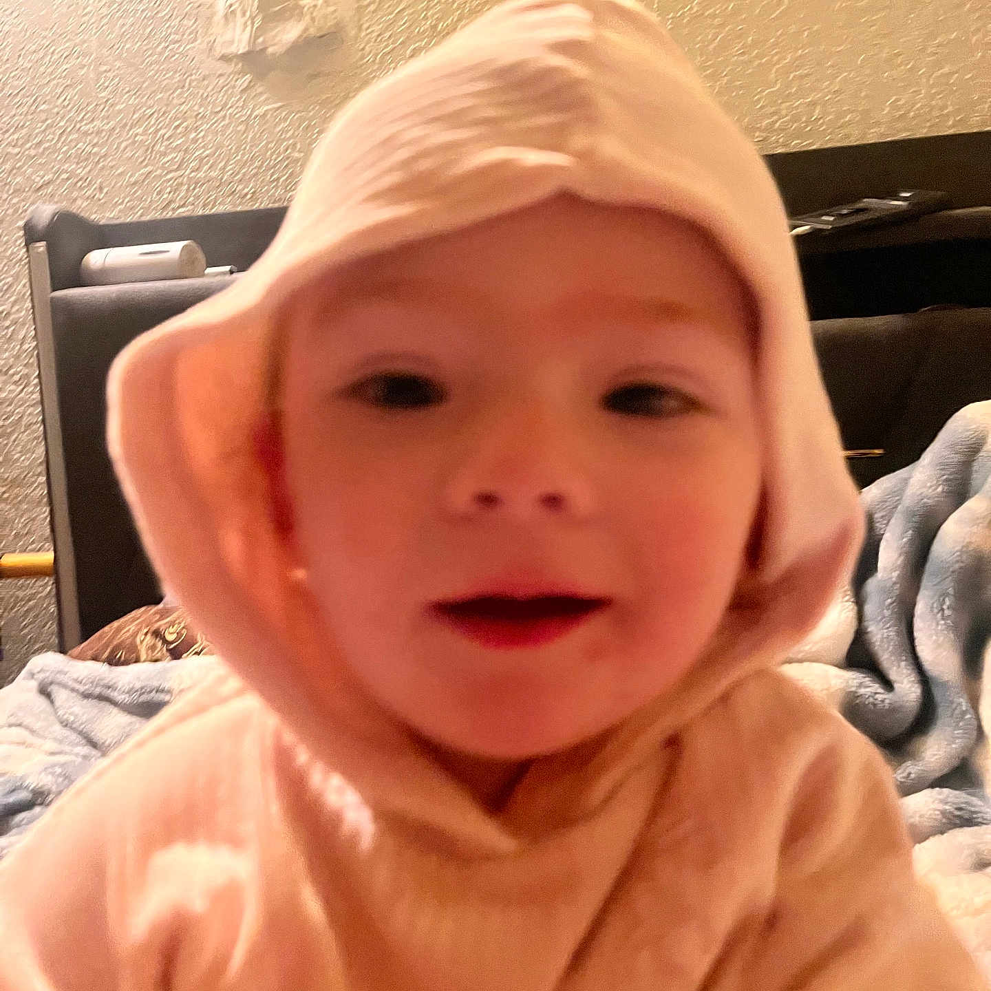 Ellie is registered to the contest to win money with this photo: child, hood, indoor, cozy, blurred, portrait, baby, face, clothing, young, soft_light, warm_tone, blanket, furniture, bedroom, person, expression, cute, casual, close_up