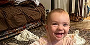 Ellie joined the competition — help win amazing prizes! baby, smiling, crawling, indoor, rug, shoe, blanket, couch, door, floor, happy, child, person, clothing, home, living_room, toy, pattern, carpet, infant