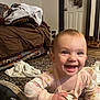 Ellie joined the competition — help win amazing prizes! baby, smiling, crawling, indoor, rug, shoe, blanket, couch, door, floor, happy, child, person, clothing, home, living_room, toy, pattern, carpet, infant