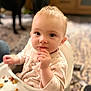 baby, blurred_background, carpet, child, clothing, curious, cute, expression, face, floor, food, furniture, hand, high_chair, home, indoor, person, seated, tray, young_child