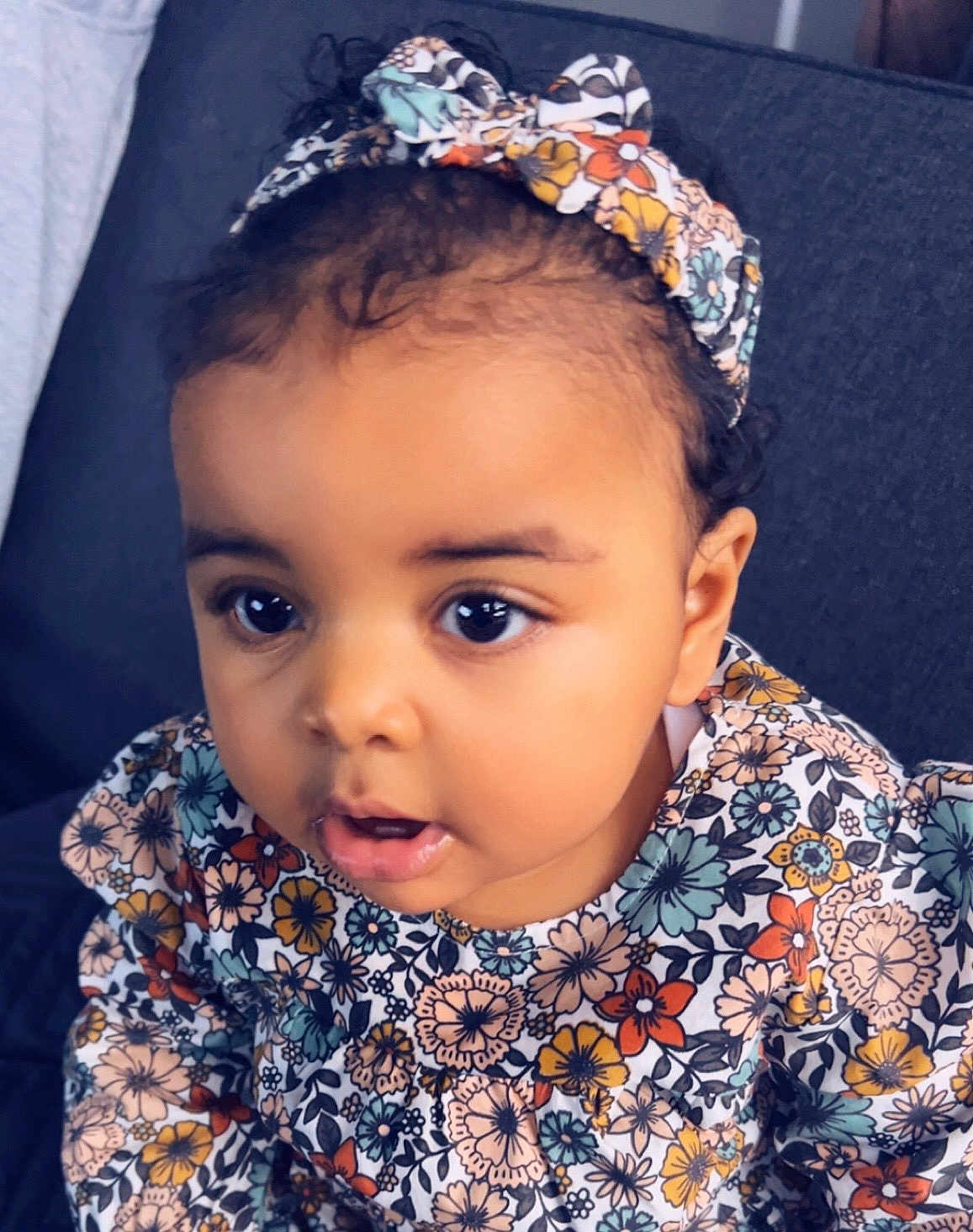 Amy-Laïyla a rejoint le concours — aidez-le/la à gagner de superbes lots ! baby, child, colorful, couch, curly_hair, cute, expression, eyes, fabric, face, floral, girl, headband, indoor, mouth, patterned_clothing, person, portrait, sitting, young_child