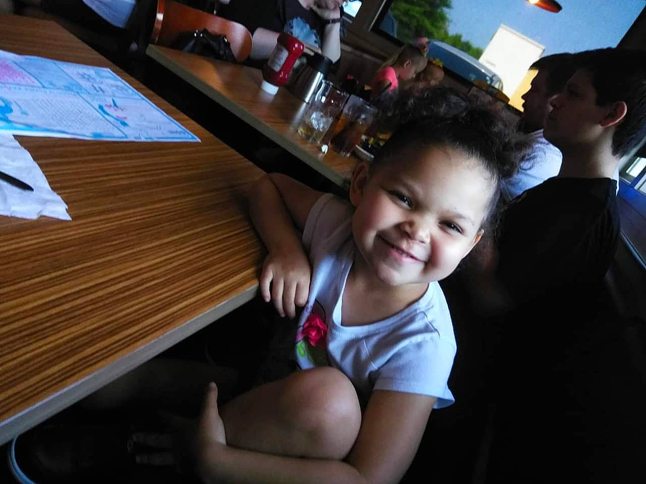 Elisha is registered to the contest to win money with this photo: child, desk, event, fun, happy, hardwood, human_leg, joy, leg, leisure, person, recreation, shorts, smile, table, thigh, toddler, travel, tree, under_exposed