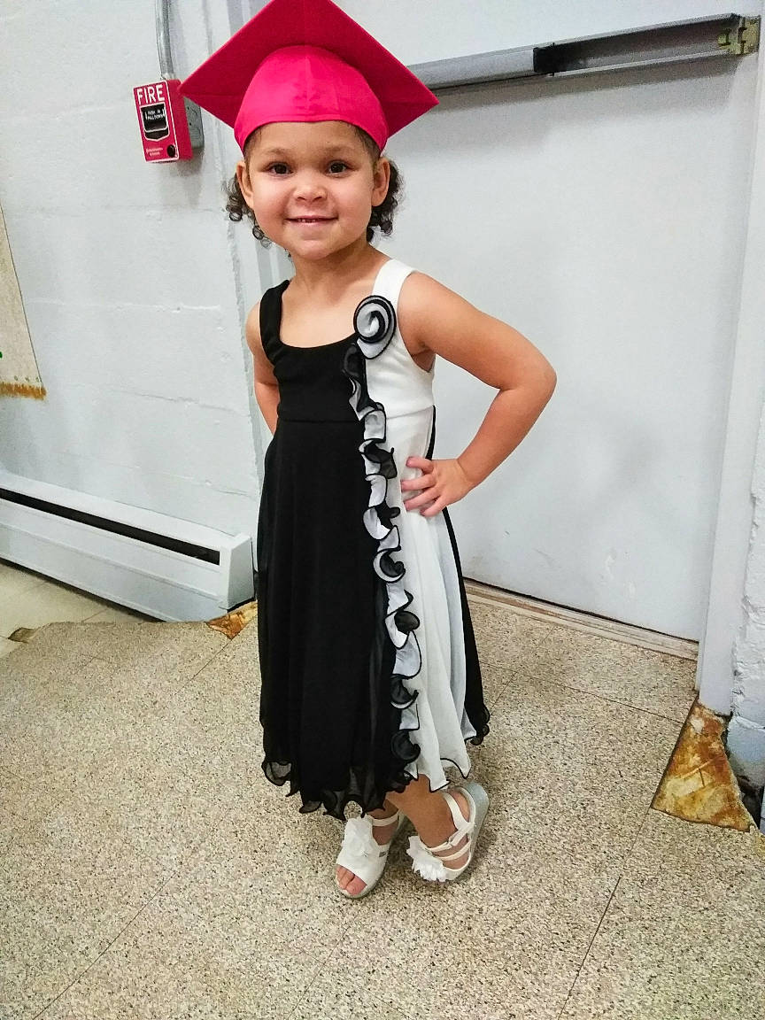 Elisha is registered to the contest to win money with this photo: academic_dress, child, costume_hat, day_dress, dress, event, fashion_accessory, fashion_design, formal_wear, fun, happy, hat, headwear, joy, mortarboard, one_piece_garment, person, sandal, sleeve, smile