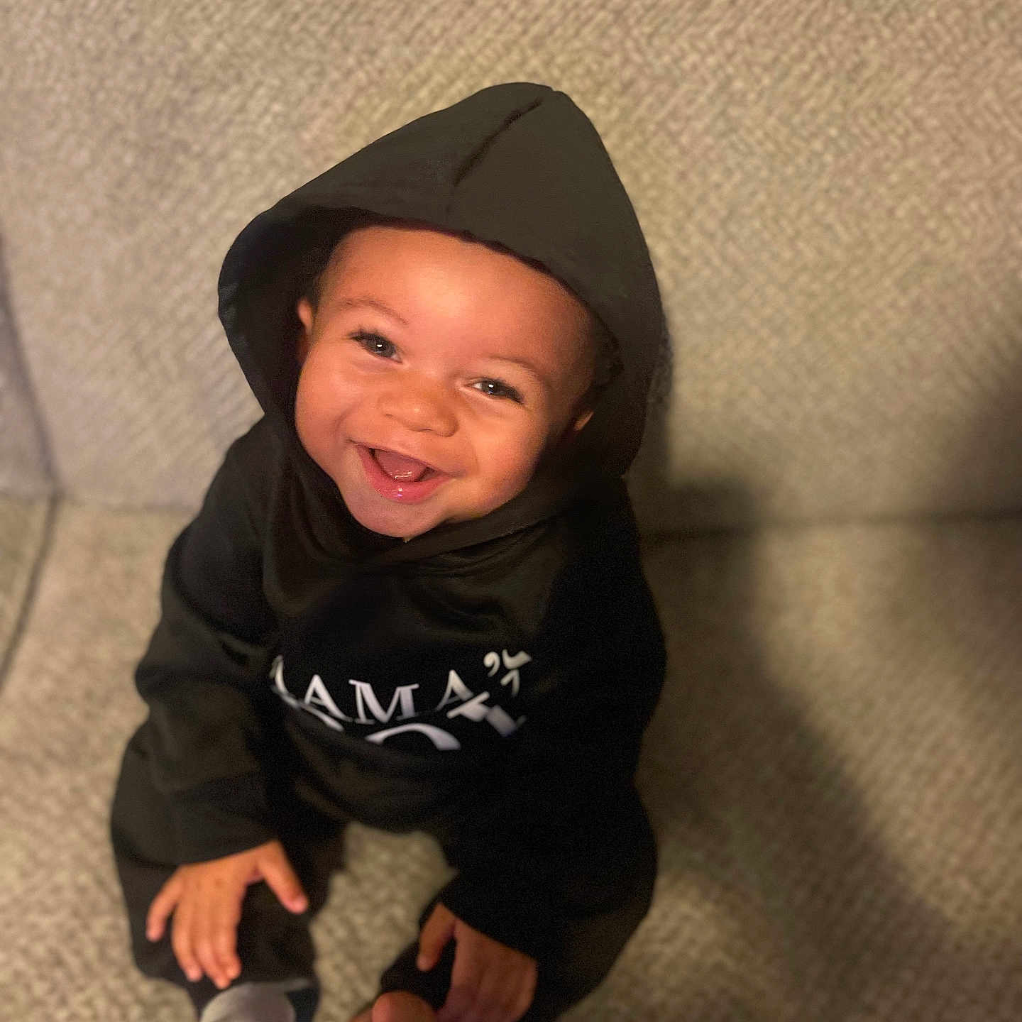 Alexander joined the competition — help win amazing prizes! baby, child, smile, hoodie, black_clothing, carpet, indoor, pacifier, sitting, happy, cute, face, young_child, infant, one_person, casual_clothing, portrait, looking_up, human, toes