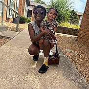 Harlow joined the competition — help win amazing prizes! woman, toddler, child, outdoor, sidewalk, building, brick, greenery, sunglasses, smile, holding, dress, white_shoes, purse, happy, person, nature, sunlight, casual, crouching