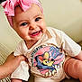 baby, child, smiling, headband, pink, bow, tshirt, mickey_mouse, sitting, happy, hand, indoor, cute, portrait, person, clothing, infant, cheerful, face, skin