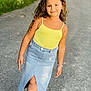 Sarah participe au concours pour gagner de l'argent avec cette photo : child, girl, curly_hair, yellow_top, denim_skirt, sidewalk, outdoor, greenery, smile, bracelet, casual, fashion, portrait, person, happy, young, walking, summer, daylight, road