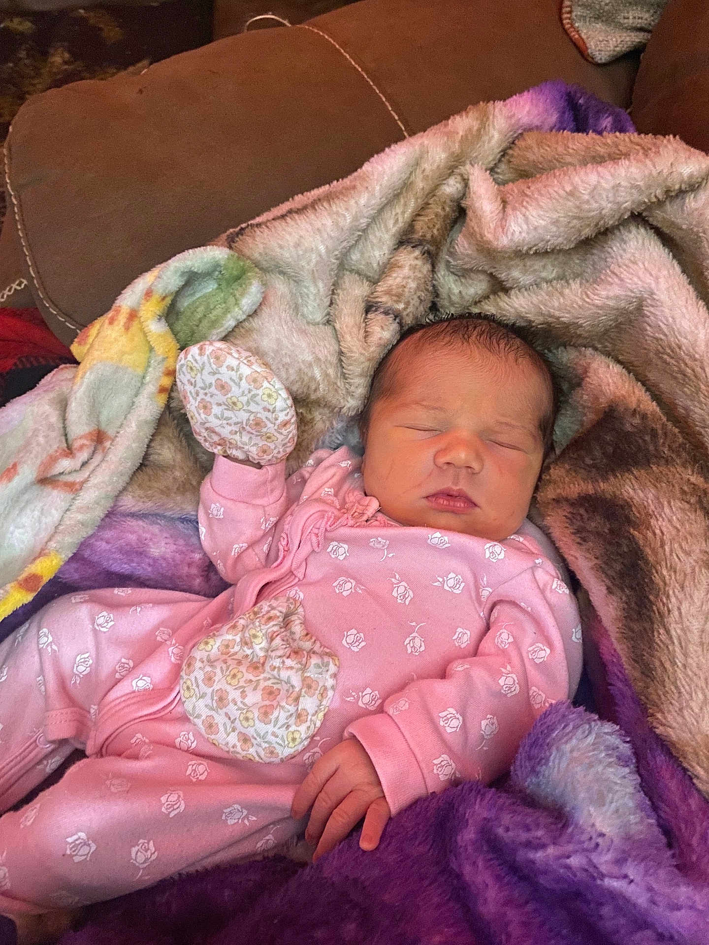 Hazel is registered to the contest to win money with this photo: baby, newborn, sleeping, blanket, pink_clothing, onesie, couch, soft_texture, hand, face, peaceful, indoor, floral_pattern, infant, cute, resting, child, warm, cozy, portrait