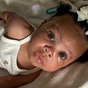 Oaklynn joined the competition — help win amazing prizes! baby, infant, child, face, eyes, curly_hair, bows, white_bow, blanket, soft_texture, clothing, tank_top, close_up, portrait, skin, cute, young_child, lying_down, expression, indoor