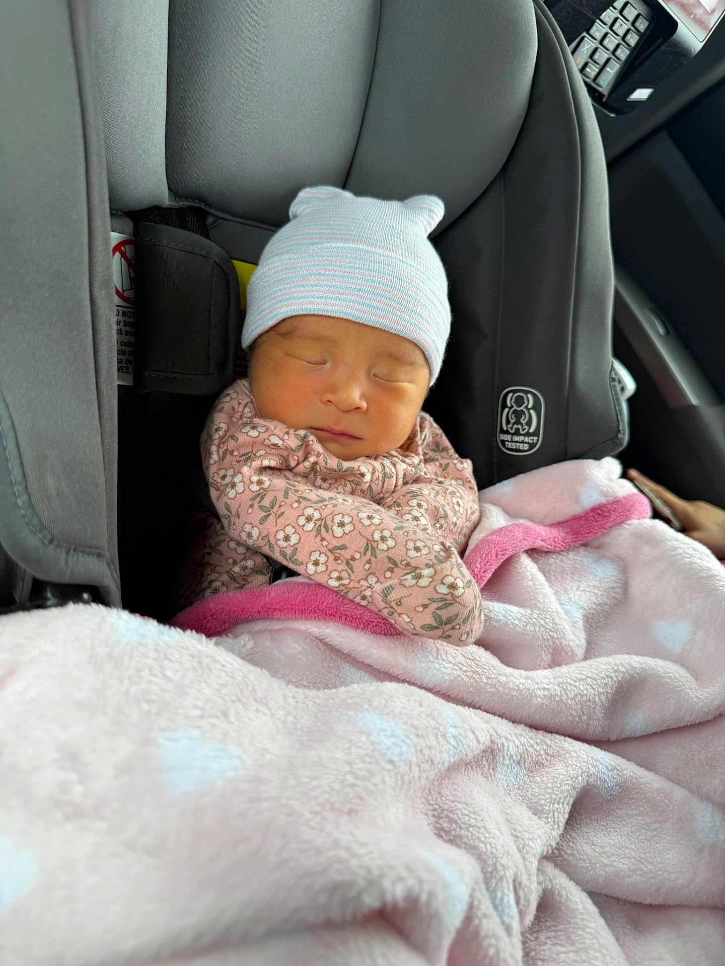 Penelope is registered to the contest to win money with this photo: baby, newborn, car_seat, blanket, sleeping, hat, floral_clothing, pink, cozy, child, infant, seatbelt, car_interior, soft_texture, cute, peaceful, wrapped, warm, child_seat, portrait