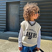 Isaïah a rejoint le concours — aidez-le/la à gagner de superbes lots ! blue_jeans, casual_clothing, child, concrete, curly_hair, daylight, door, fashion, los_angeles_lakers, metal_wall, outdoor, person, shadow, side_profile, standing, stroller, sunglasses, sunlight, sweater_vest, urban